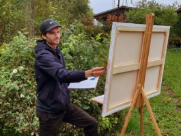 Tobias Leuenberger steht an der Feldstaffelei und hat eine grosse Leinwand eingespannt. 