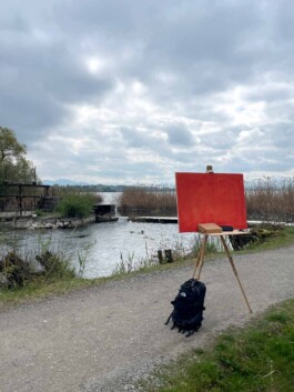 Eine Feldstaffelei mit orange grundierter Leinwand steht am Greifensee. 