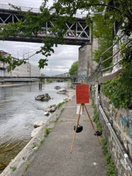 Die Feldstaffelei steht direkt an der Limmat. Eine orange grundierte Leinwand ist darauf eingespannt. 
